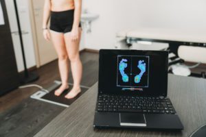 Young adult woman is standing on a medical pressure scanner to analyze her footprint and realize new shoe insoles to improve her posture