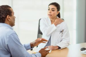 doctor asks male patient about shoulder pain