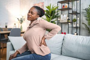 woman suffering with back pain while sitting at home